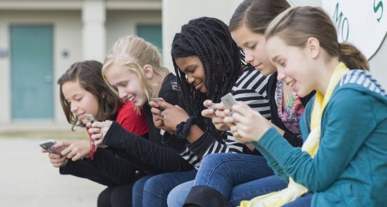Un grupo de niñas se afanan con los mensajes en sus teléfonos móviles. / Getty / Kevin Dodge