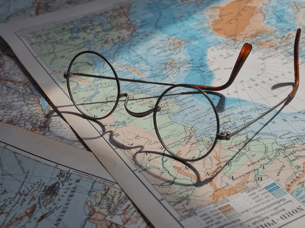 Unas gafas sobre un mapa antiguo que muestra continentes y océanos.